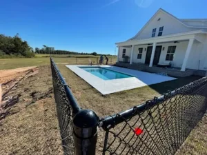 A small chain link fence surrounds a pool in a rural area